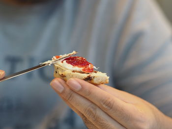 Close-up of person spreading jam on scone