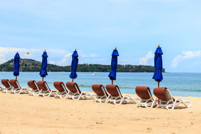 Parasols on beach against blue sky