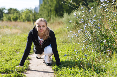 Young woman exercising while sitting on field 