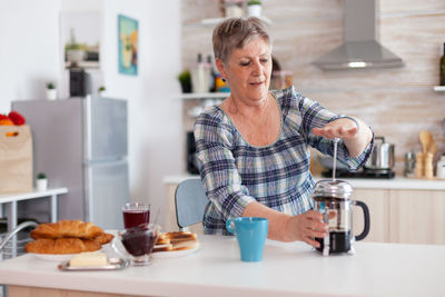 Senior woman preparing coffee at home