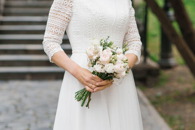 The bride holds a beautiful wedding bouquet of white flowers in her hands