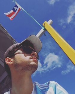 Low angle view of man with umbrella against sky