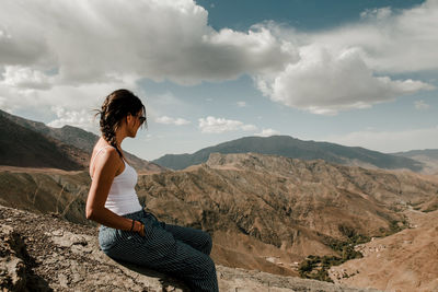 Brunette girl with sunglasses looking towards the valley of the moroccan high atlas