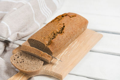 Homemade sourdough rye bread sliced on a cutting board on white table, close-up image