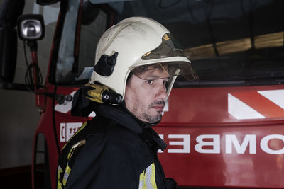 Close-up of firefighter standing by firetruck