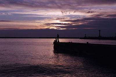 Silhouette people on beach against sky during sunset