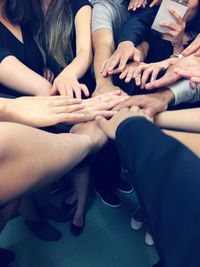 Low section of people stacking hands over carpet