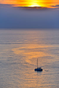 Sailboat sailing on sea against sky during sunset