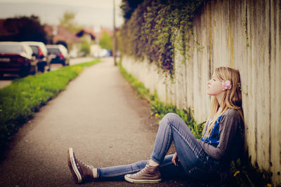 Side view of young woman sitting outdoors