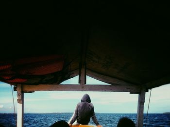 Rear view of people standing at beach against clear sky