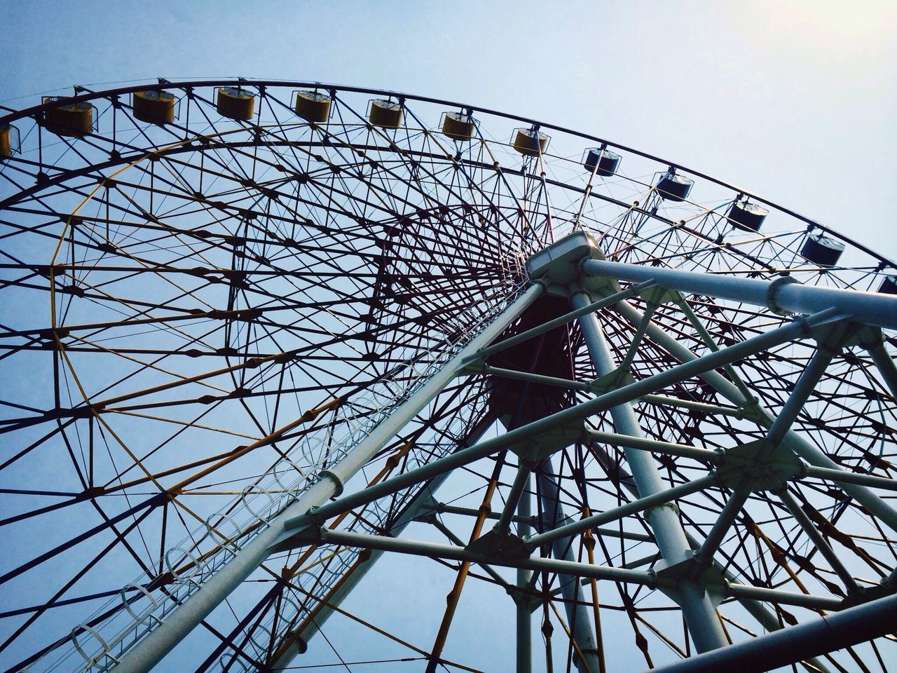 low angle view, ferris wheel, amusement park, amusement park ride, arts culture and entertainment, sky, clear sky, metal, built structure, architecture, rollercoaster, metallic, day, big wheel, outdoors, no people, fairground ride, fairground, large, fun