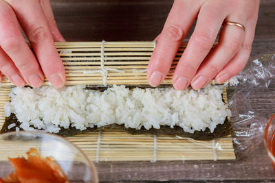 Cropped hands preparing sushi on table