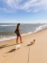 Rear view of woman standing at beach against sky