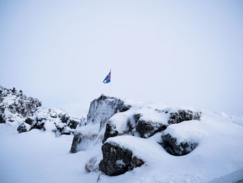 Low angle view of flag against clear sky during winter