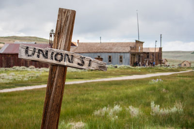 Information sign on wooden post on field against sky