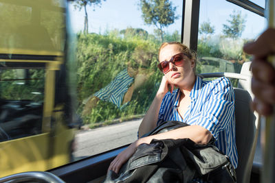 Mid adult woman wearing sunglasses sleeping at bus