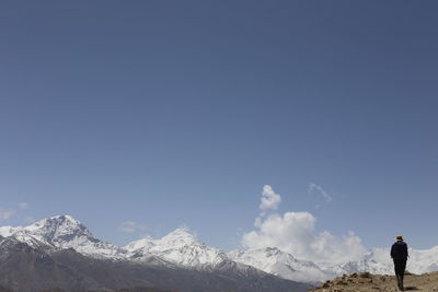 Man standing against snowcapped mountain and sky