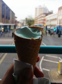 Cropped hand of person holding ice cream cone in bus