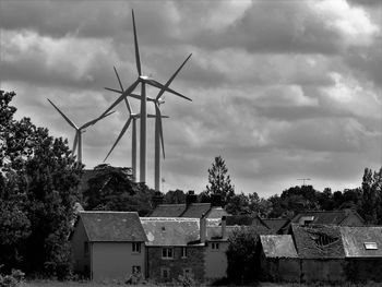 Wind turbines and buildings against sky