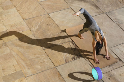 Young woman practicing yoga on mat during sunny day