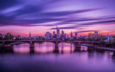 Bridge on river against sky at dusk