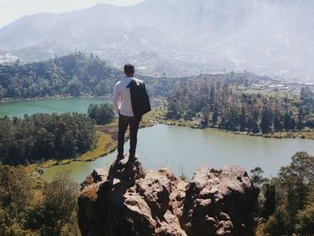 Rear view of man standing by lake