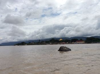 Scenic view of sea and mountains against cloudy sky