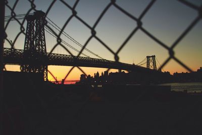 Low angle view of silhouette williamsburg bridge over east river at sunset