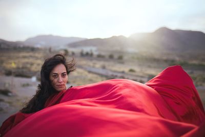 Portrait of woman in red dress against sky