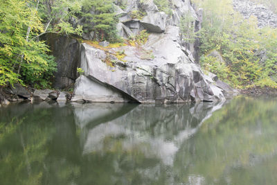 Scenic view of calm river by cliff