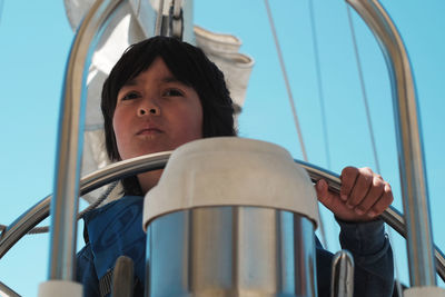 Close-up of boy holding steering wheel while traveling in sailboat