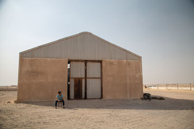 Man sitting outside abandoned warehouse 