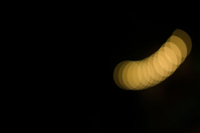 Low angle view of illuminated lamp against black background