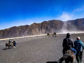 People on land against mountain range