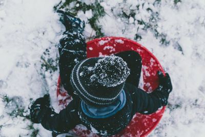 Ice embedded into young boys stocking cap beanie hat as he slides down hill during the winter snow