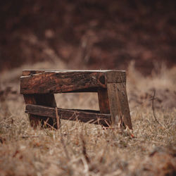 Close-up of old abandoned bench on field