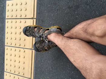 Low section of man sitting by tactile paving on road