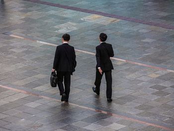 Rear view of two men standing on floor