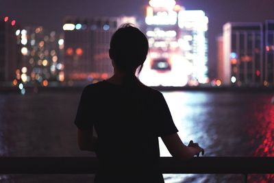 Rear view of silhouette man standing in illuminated city at night