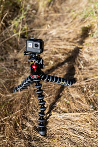 Small action camera mounted on tripod in bright sunshine in field