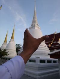 Low angle view of hand against temple building