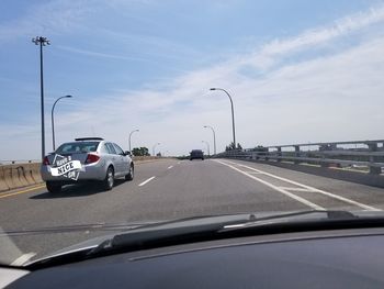 Vehicles on road against sky seen through car windshield