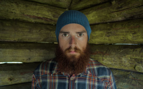 Portrait of bearded man by wooden wall