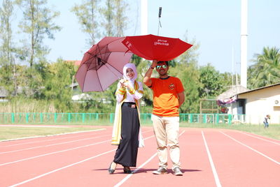 Full length portrait of a man with red umbrella