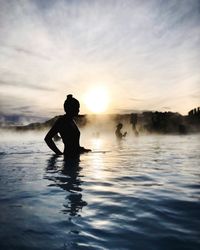 Silhouette woman in hot spring during sunrise