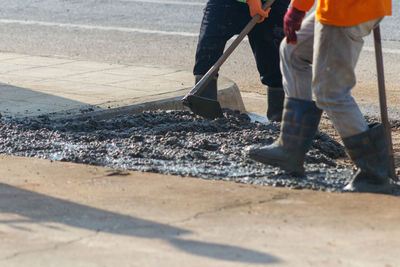 Low section of men working on road in city