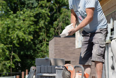 Masonry worker the bricklayer makes the facade of the house from gray bricks