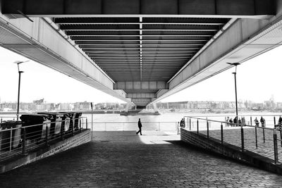 Man walking under bridge over river