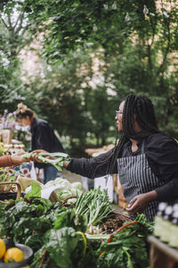 Vegetable vendor selling scallion to customer at farmer's market