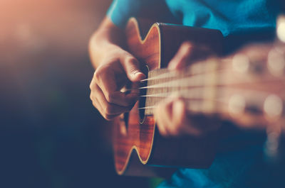 Midsection of man playing guitar